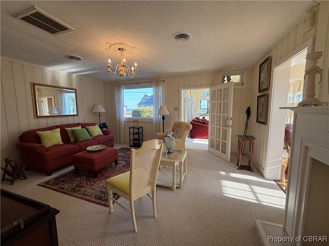 living area featuring light carpet, visible vents, a textured ceiling, and an inviting chandelier