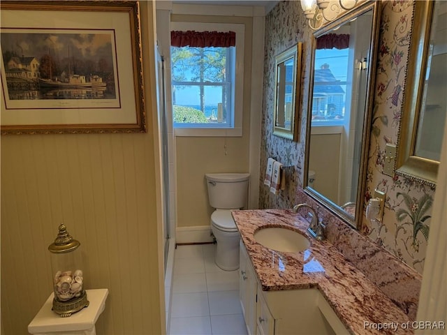 bathroom with vanity, baseboards, wallpapered walls, tile patterned flooring, and toilet