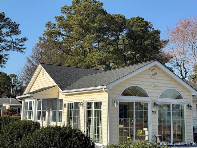 view of property exterior with a sunroom and a shingled roof