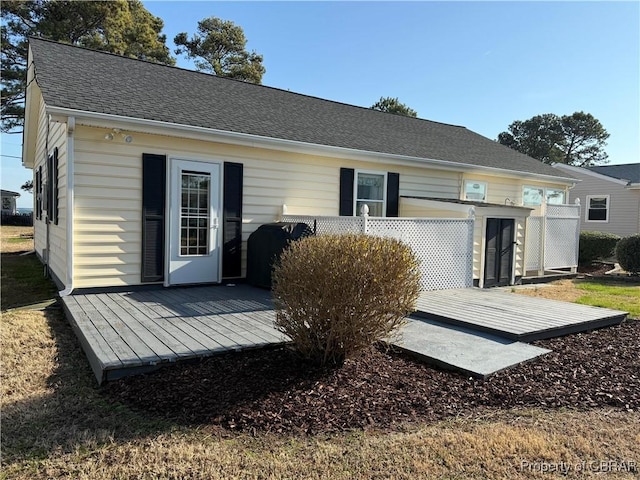 back of property with a deck and a shingled roof