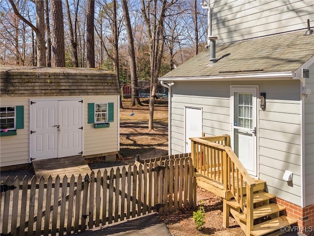 doorway to property with fence and roof with shingles