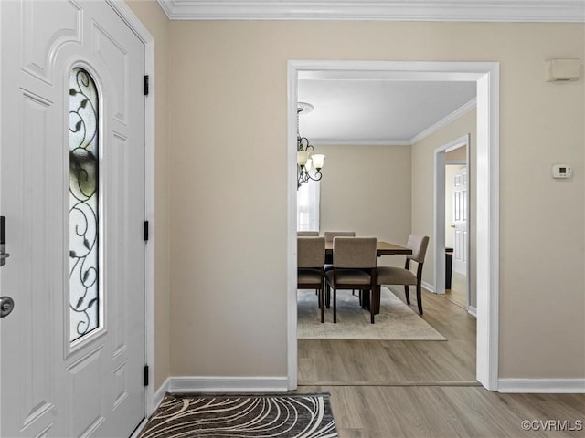 entrance foyer featuring light wood finished floors, a chandelier, baseboards, and ornamental molding