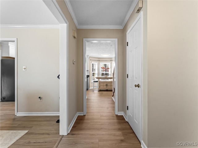 hallway featuring wood finished floors, baseboards, and ornamental molding