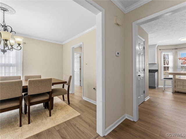 dining space with an inviting chandelier, crown molding, wood finished floors, and baseboards