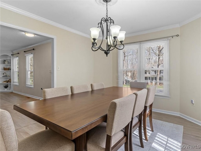 dining room featuring light wood-type flooring, baseboards, a chandelier, and crown molding