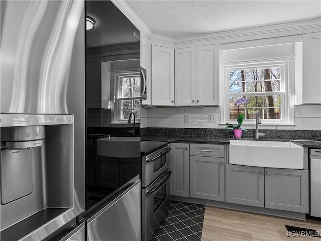 kitchen with a sink, stainless steel appliances, tasteful backsplash, and dark stone counters