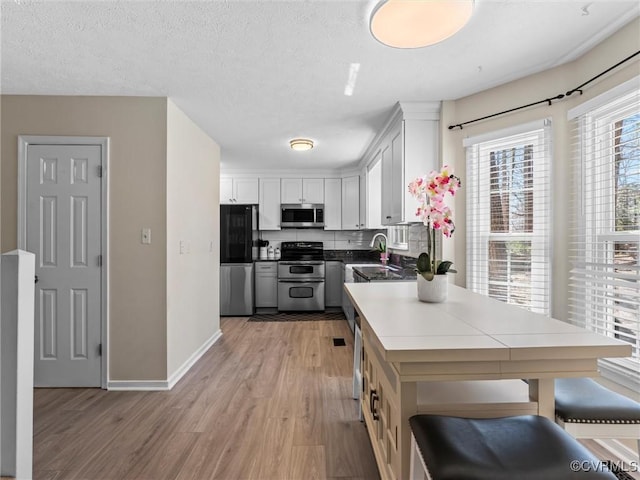 kitchen with white cabinetry, light wood-type flooring, appliances with stainless steel finishes, and a sink