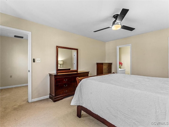 bedroom featuring visible vents, baseboards, ceiling fan, ensuite bathroom, and light colored carpet