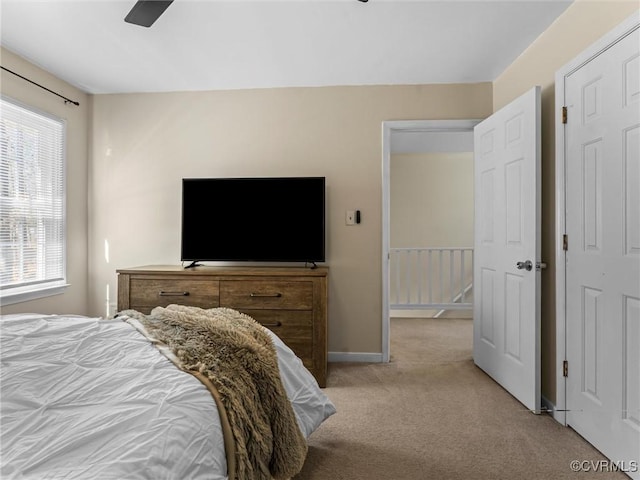 bedroom with multiple windows, a ceiling fan, baseboards, and light carpet