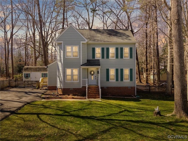 colonial home with a front lawn, fence, roof with shingles, and crawl space