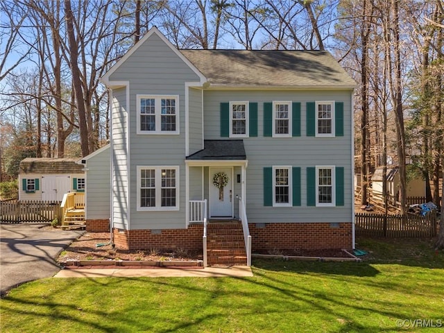 view of front facade with fence, crawl space, a front yard, an outbuilding, and a storage unit