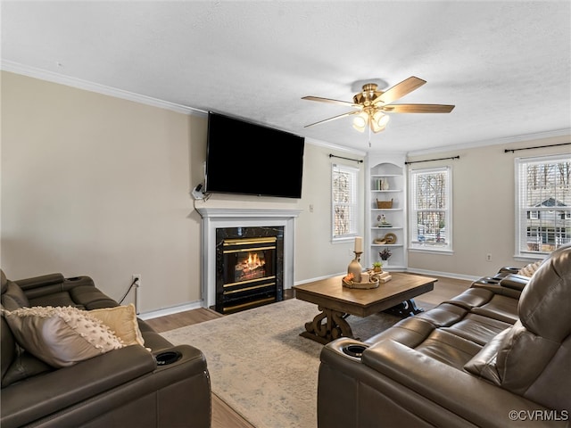 living room with light wood-style flooring, ornamental molding, a premium fireplace, baseboards, and ceiling fan