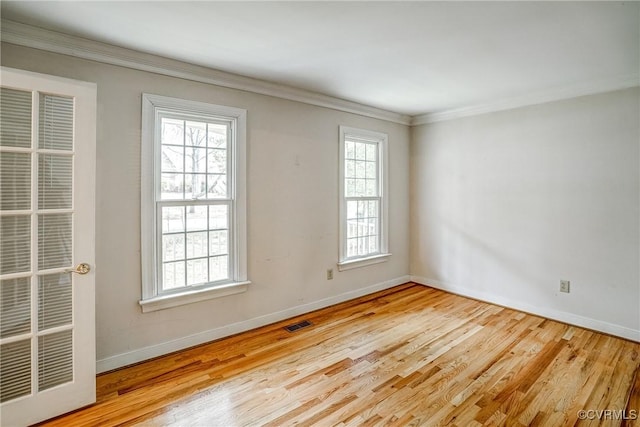 spare room with visible vents, a healthy amount of sunlight, wood finished floors, and crown molding