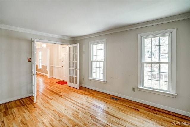 spare room with visible vents, baseboards, light wood-style flooring, and ornamental molding