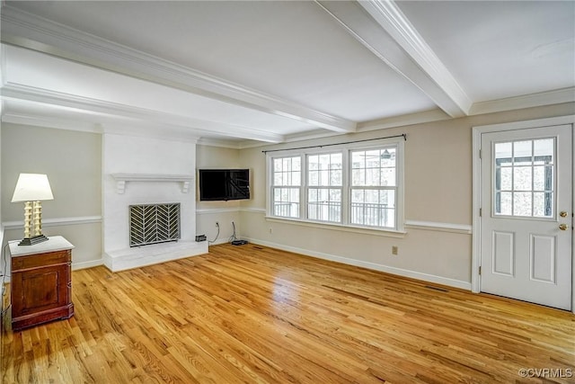 living area with beamed ceiling, a brick fireplace, light wood-style flooring, and a healthy amount of sunlight