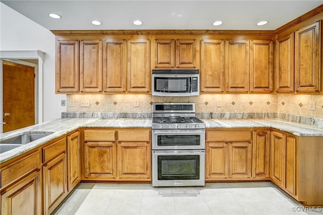 kitchen with light countertops, light tile patterned flooring, brown cabinetry, and appliances with stainless steel finishes