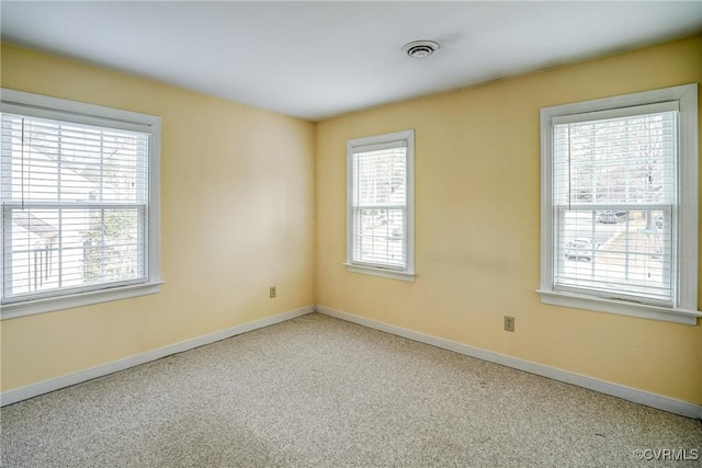 unfurnished room featuring plenty of natural light, baseboards, and visible vents