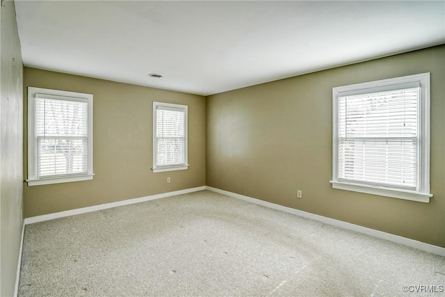 unfurnished room with carpet flooring, visible vents, and baseboards