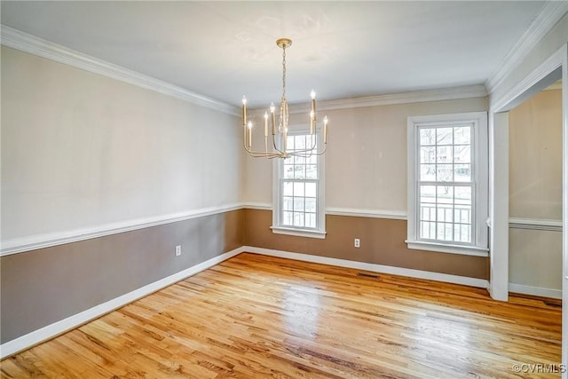 unfurnished dining area with ornamental molding, an inviting chandelier, baseboards, and wood finished floors