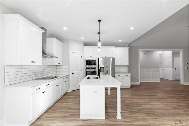 kitchen featuring light countertops, wall chimney exhaust hood, wood finished floors, and appliances with stainless steel finishes