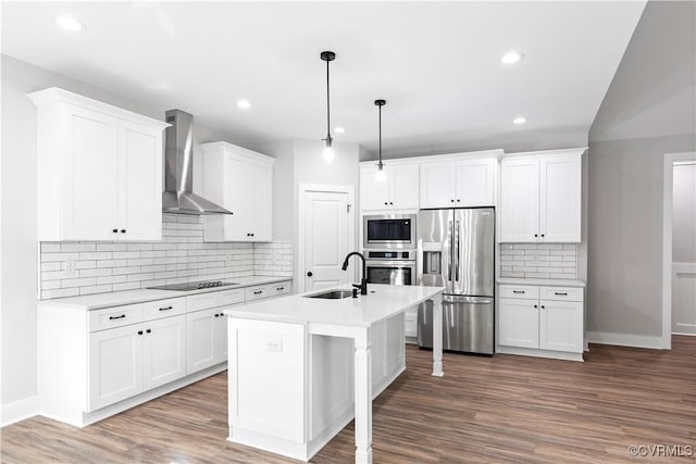 kitchen featuring stainless steel appliances, light countertops, wall chimney range hood, and a sink