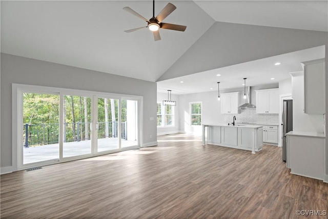 unfurnished living room with a ceiling fan, baseboards, high vaulted ceiling, recessed lighting, and light wood-style floors