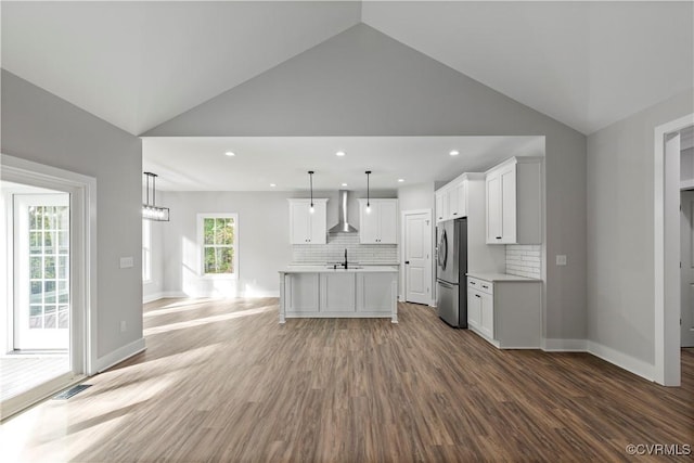 kitchen featuring wall chimney range hood, freestanding refrigerator, light wood-style floors, light countertops, and decorative backsplash