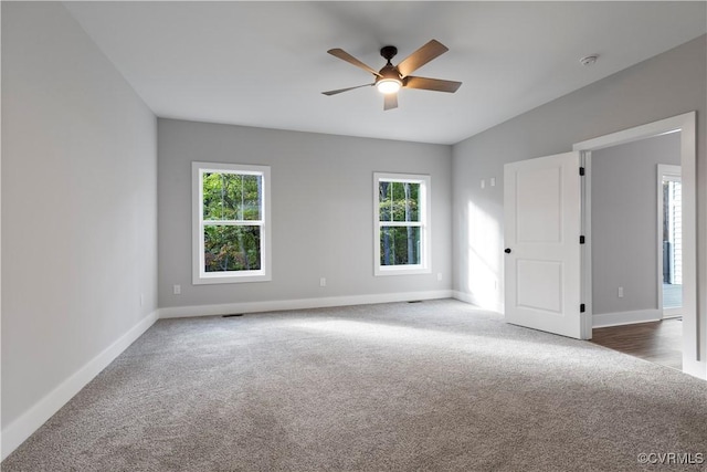 unfurnished room featuring a healthy amount of sunlight, baseboards, and carpet