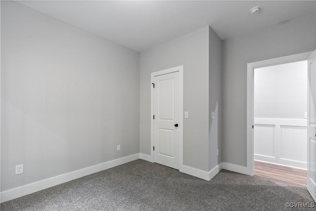 unfurnished bedroom featuring dark carpet and baseboards