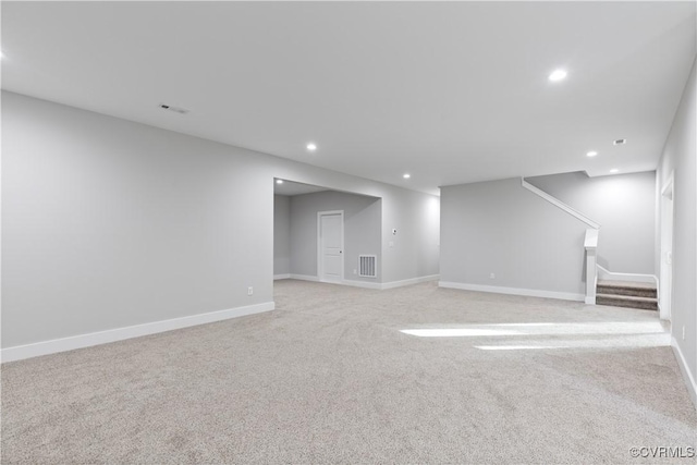 finished basement featuring visible vents, light carpet, recessed lighting, stairway, and baseboards