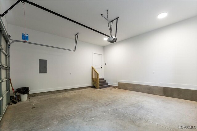 garage featuring electric panel, a garage door opener, and baseboards