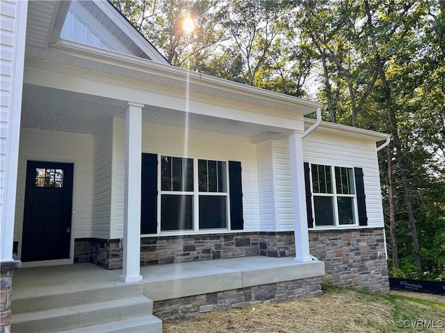 entrance to property featuring stone siding and a porch