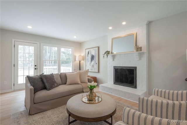 living area featuring a brick fireplace, recessed lighting, and light wood-style floors