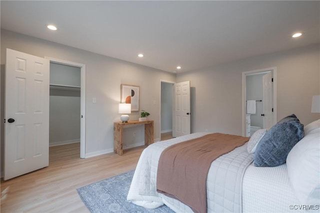 bedroom featuring baseboards, ensuite bath, recessed lighting, light wood-style floors, and a walk in closet