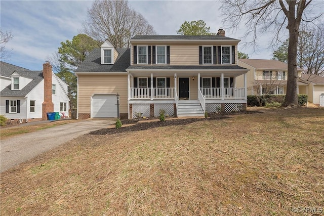 colonial home featuring a porch, a front lawn, driveway, and a garage