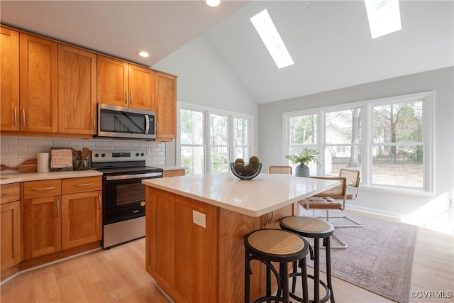 kitchen with a healthy amount of sunlight, appliances with stainless steel finishes, a breakfast bar area, and light countertops