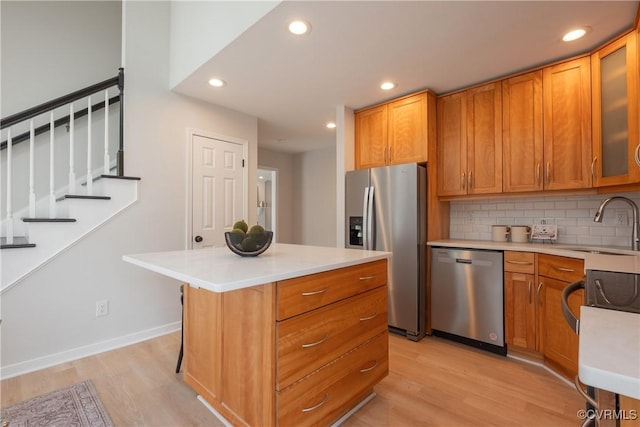 kitchen with light wood finished floors, brown cabinets, stainless steel appliances, and light countertops