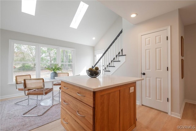 office area with lofted ceiling with skylight, recessed lighting, light wood-style flooring, and baseboards