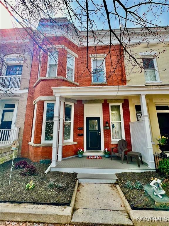 multi unit property featuring a porch and brick siding