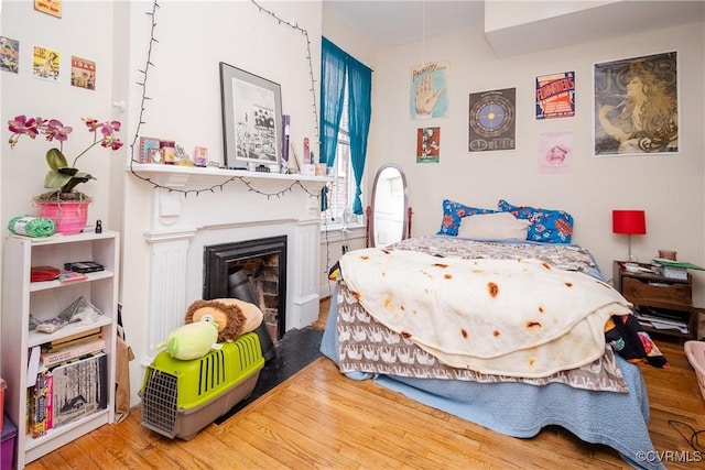 bedroom with wood finished floors and a fireplace