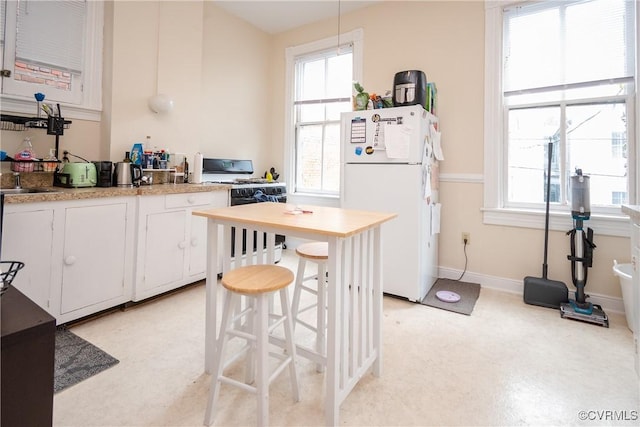 kitchen with a wealth of natural light, white cabinets, white appliances, and light countertops