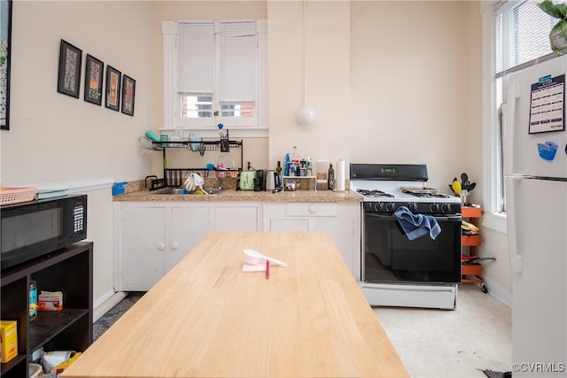 kitchen featuring white appliances, white cabinets, baseboards, and wooden counters