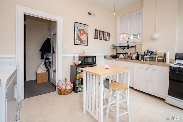 kitchen with visible vents, black appliances, white cabinets, light countertops, and light carpet