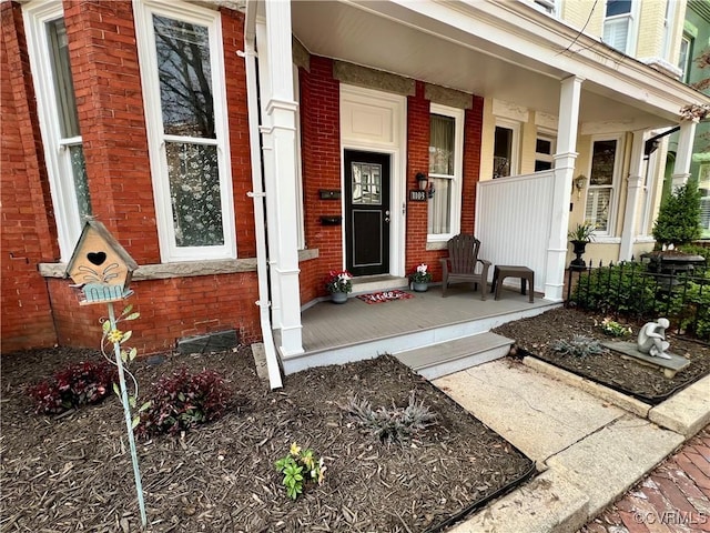 doorway to property featuring brick siding and a porch