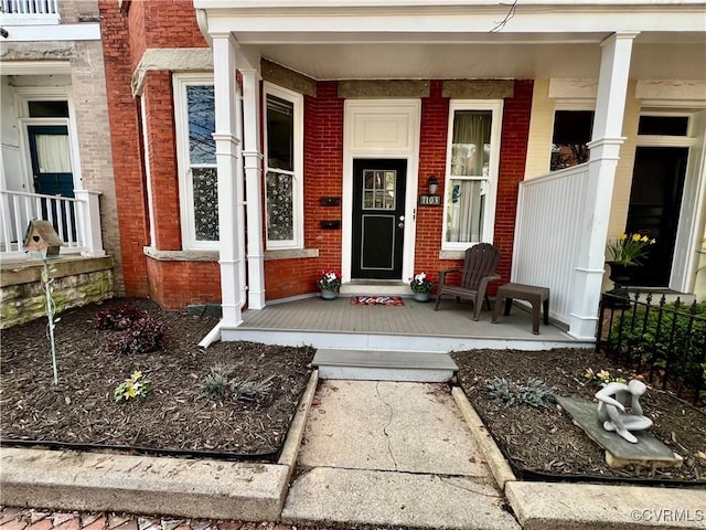 property entrance featuring brick siding and a porch