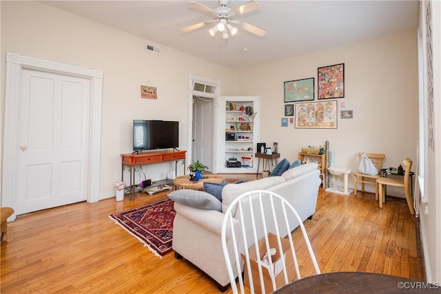 living room with visible vents, baseboards, a ceiling fan, and light wood finished floors