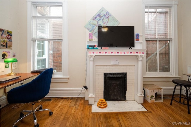 home office featuring visible vents, baseboards, a brick fireplace, and wood finished floors