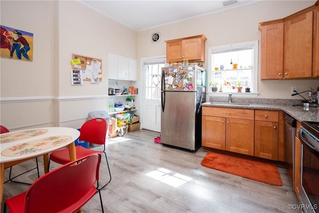 kitchen featuring a wealth of natural light, light wood finished floors, freestanding refrigerator, and a sink