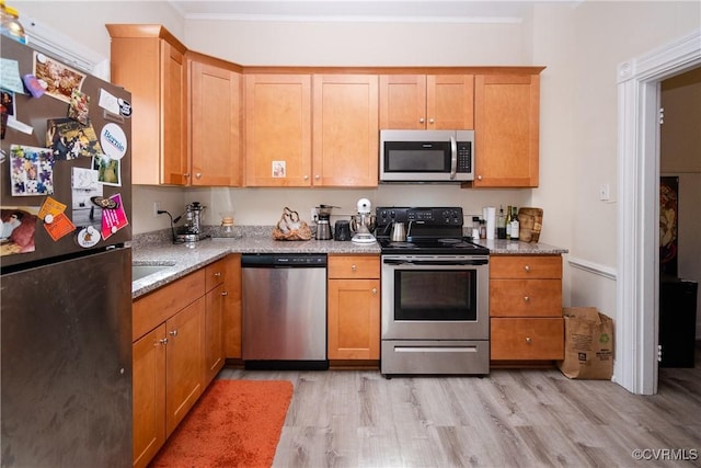 kitchen with crown molding, light stone counters, light wood-type flooring, and stainless steel appliances