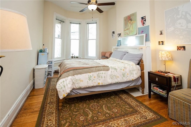 bedroom featuring baseboards, wood finished floors, and a ceiling fan